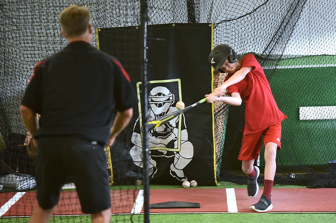 Dillon Galloway, 12, with the Kalispell Lakers 12U team, hits soft-toss from coach Jeff Berke inside the batting cage at THE FORT, an indoor multi-sport turf facility in Kalispell, on Thursday, April 4. (Casey Kreider/Daily Inter Lake)