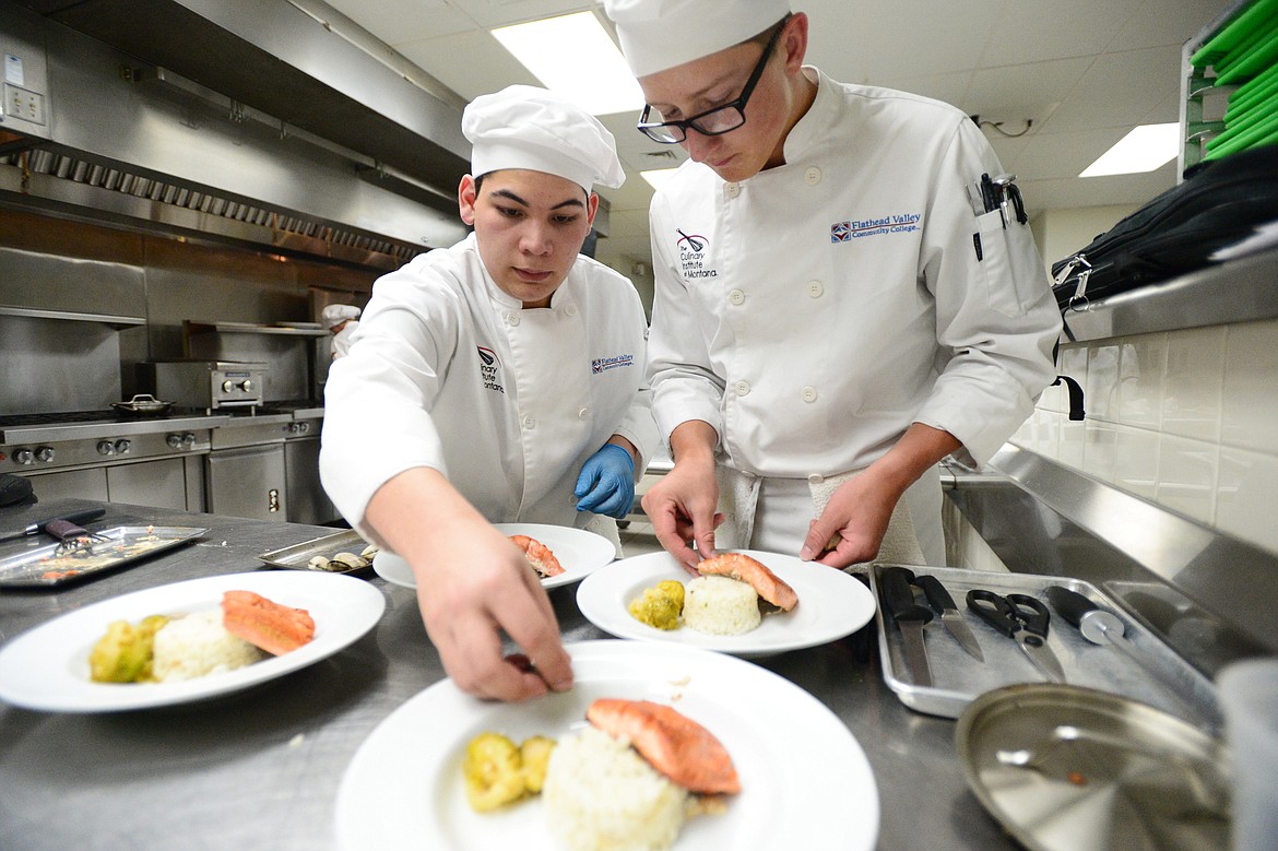 Eli Valadez, left, and Brant Barnes work on plating their salmon dishes inside the kitchen at the Culinary Institute of Montana at Flathead Valley Community College on Wednesday, April 3. (Casey Kreider/Daily Inter Lake)