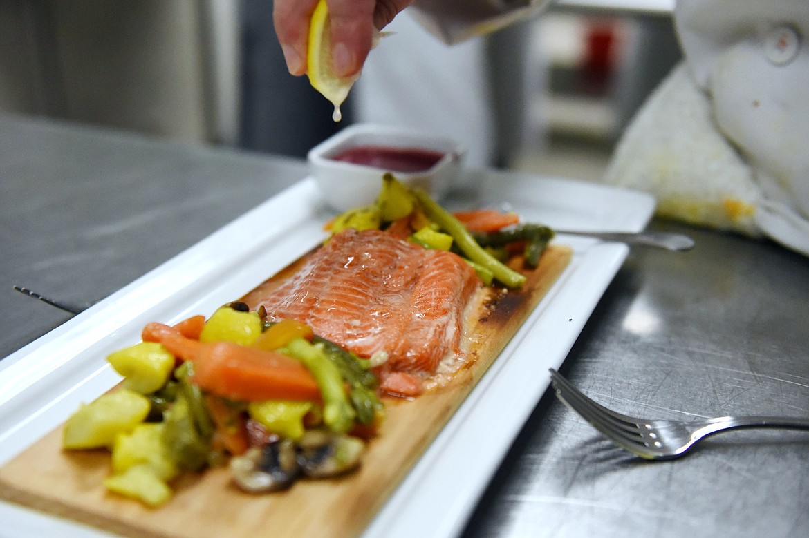 Sarah Cloninger adds a squeeze of lemon juice to the salmon in her group&#146;s Gitksan Planked Salmon dish inside the kitchen at the Culinary Institute of Montana at Flathead Valley Community College on Wednesday, April 3. (Casey Kreider/Daily Inter Lake)