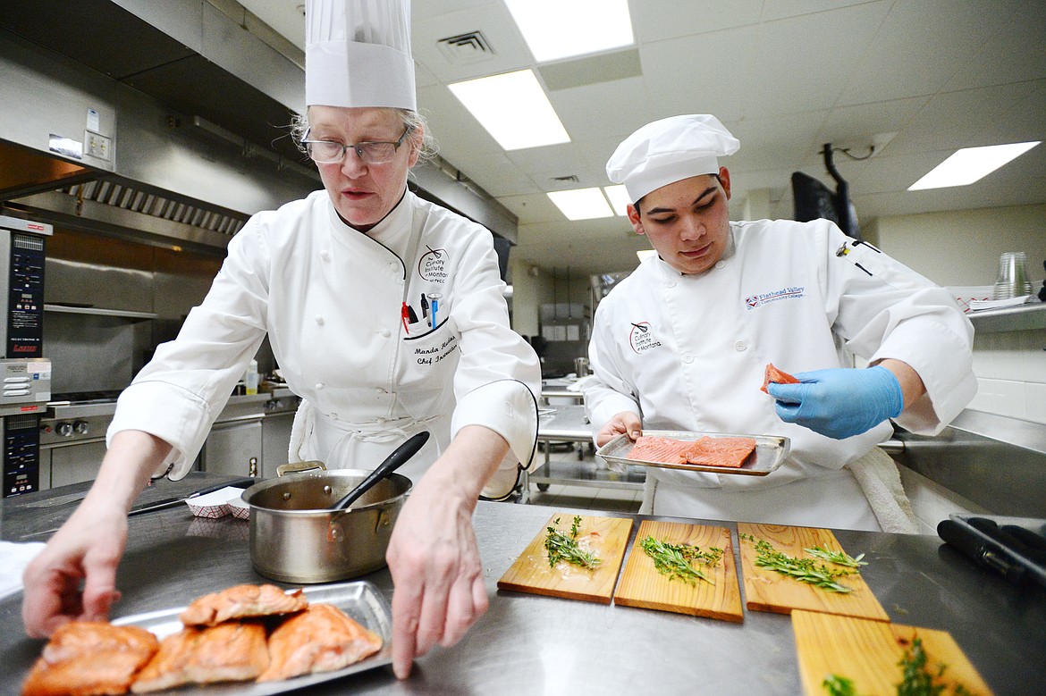 Chef instructor Manda Hudak, left, provides a few pointers to Eli Valadez as he works on his salmon dish inside the kitchen at the Culinary Institute of Montana at Flathead Valley Community College on Wednesday, April 3. (Casey Kreider/Daily Inter Lake)