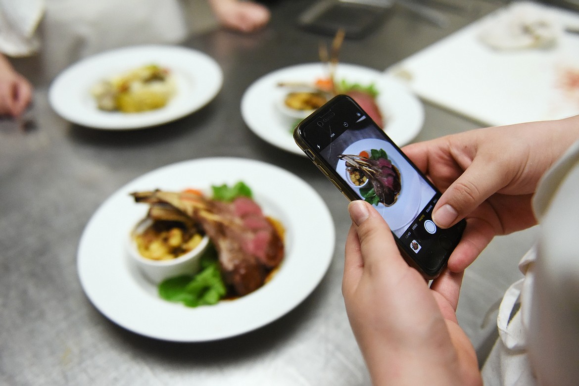 Garrason Jones snaps a photo of the Roasted Rack of Northwest Lamb dish inside the kitchen at the Culinary Institute of Montana at Flathead Valley Community College on Wednesday, April 3. (Casey Kreider/Daily Inter Lake)