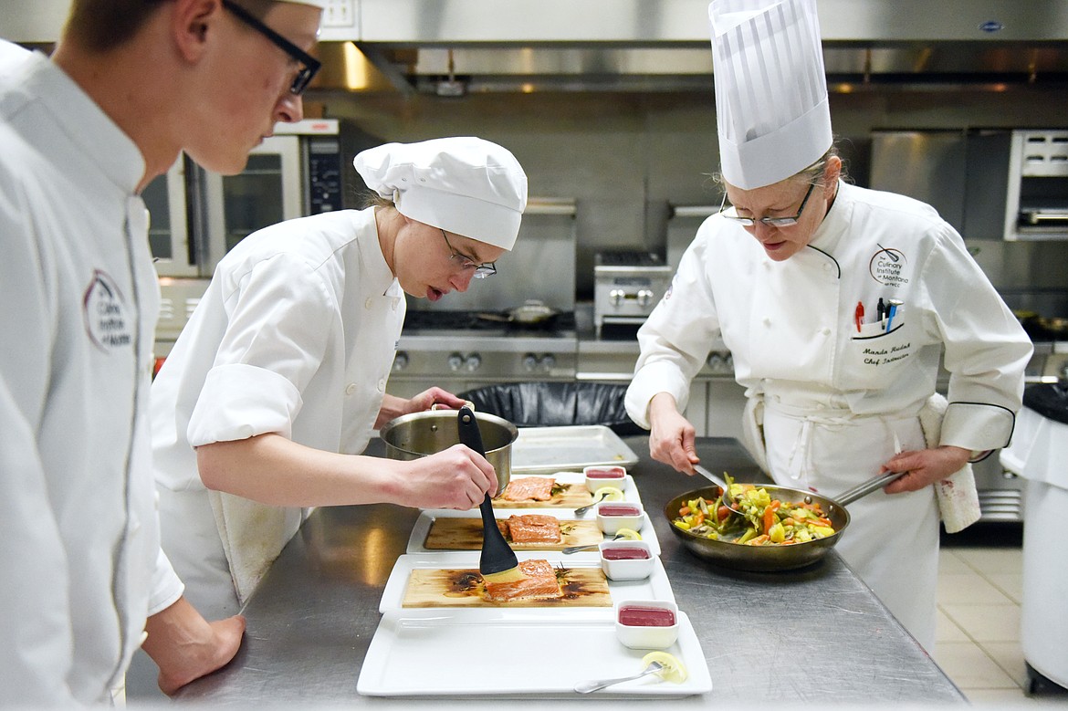 Chef instructor Manda Hudak, right, assists Hannah Troutt and Brant Barnes with their salmon dish inside the kitchen at the Culinary Institute of Montana at Flathead Valley Community College on Wednesday, April 3. (Casey Kreider/Daily Inter Lake)