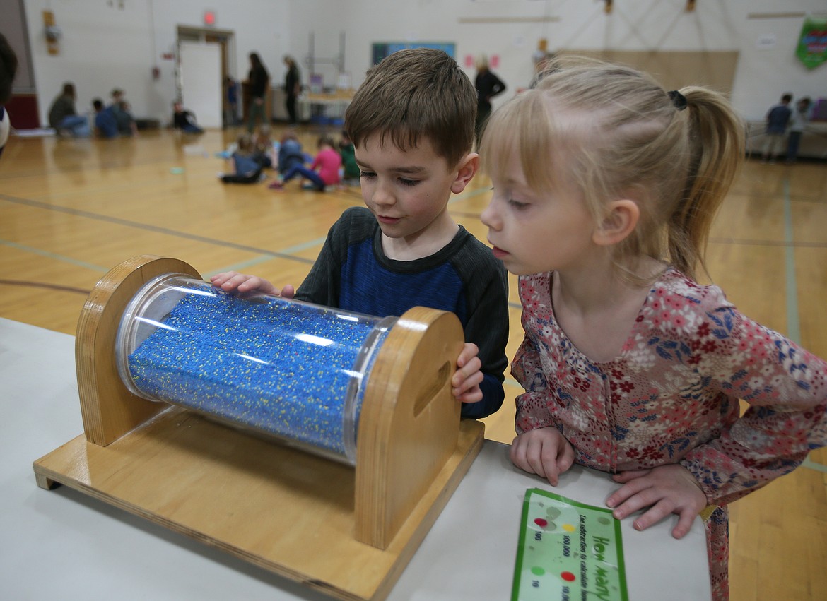 Kindergartners Cade Baldwin and Zabrina Hull inspect a tumbler filled with beads at a Science on Wheels station in the Fernan STEM Academy gym on Tuesday. (DEVIN WEEKS/Press)