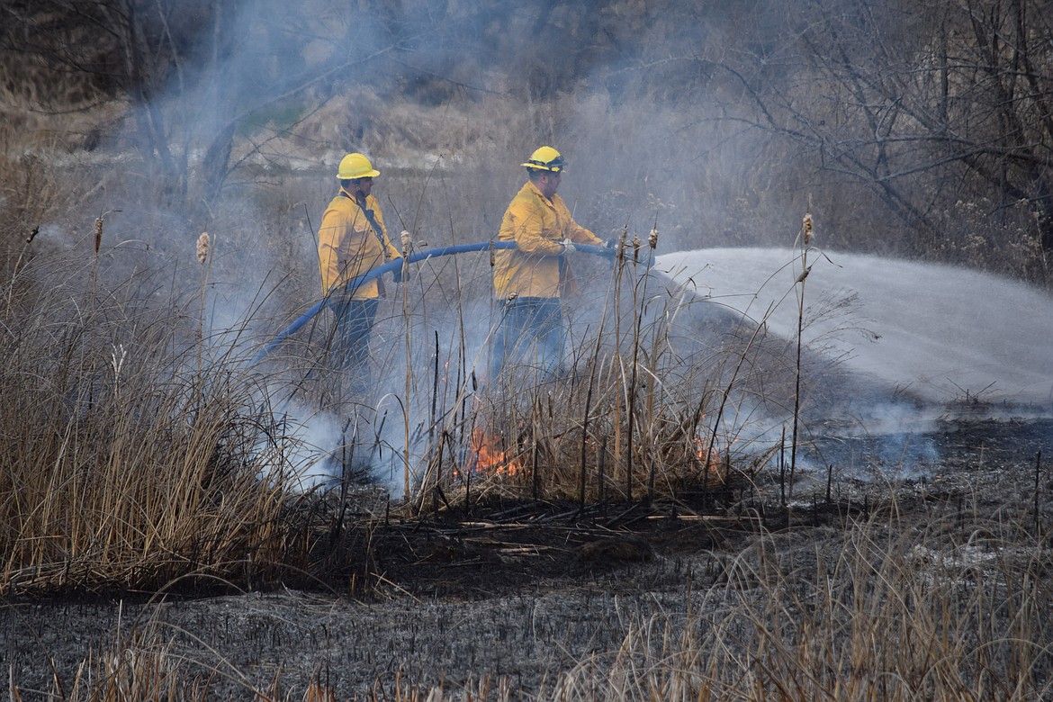 Charles H. Featherstone/Columbia Basin Herald
Moses Lake firefighters battle a small blaze on the island where SR-17 crosses Crab Creek.