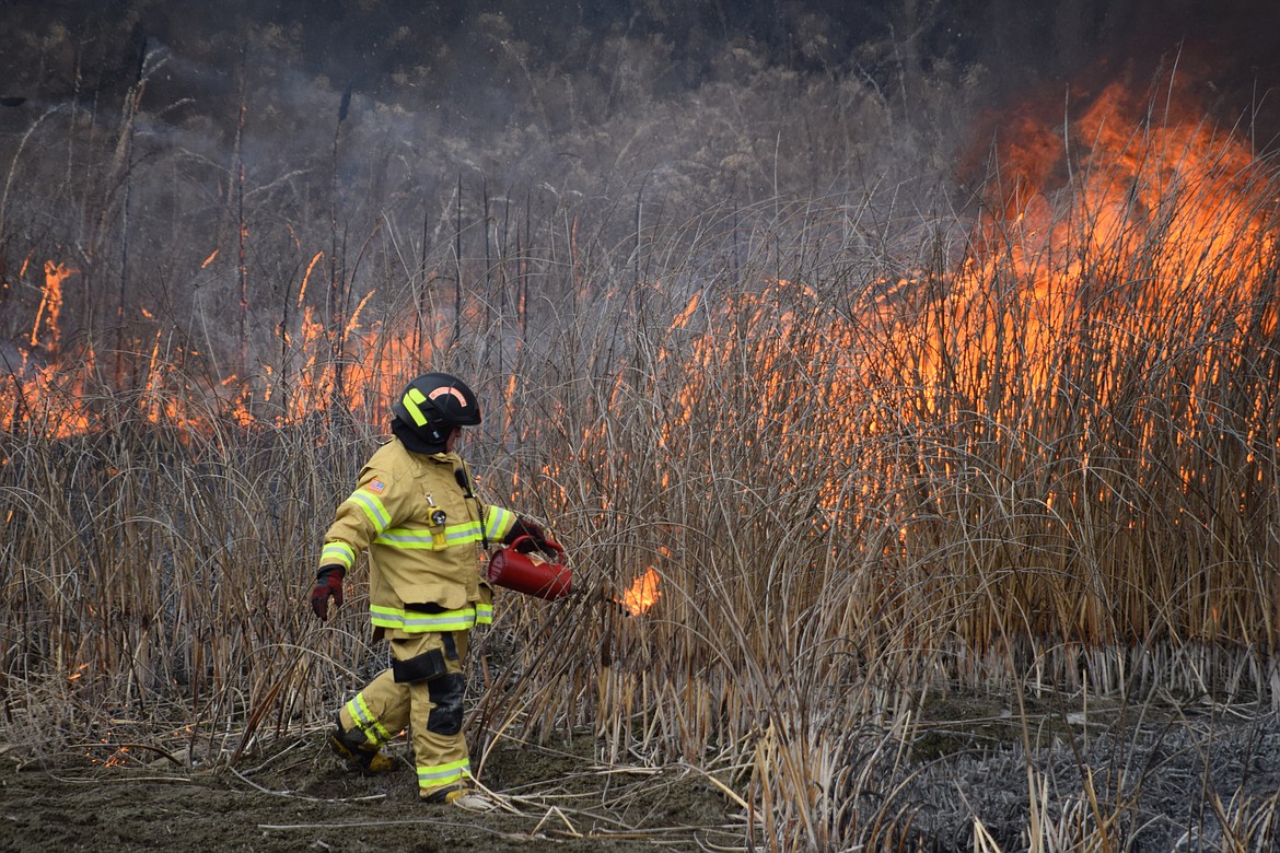 Charles H. Featherstone/Columbia Basin Herald
A Moses Lake firefighter sets a fire on the island where SR-17 crosses Crab Creek.