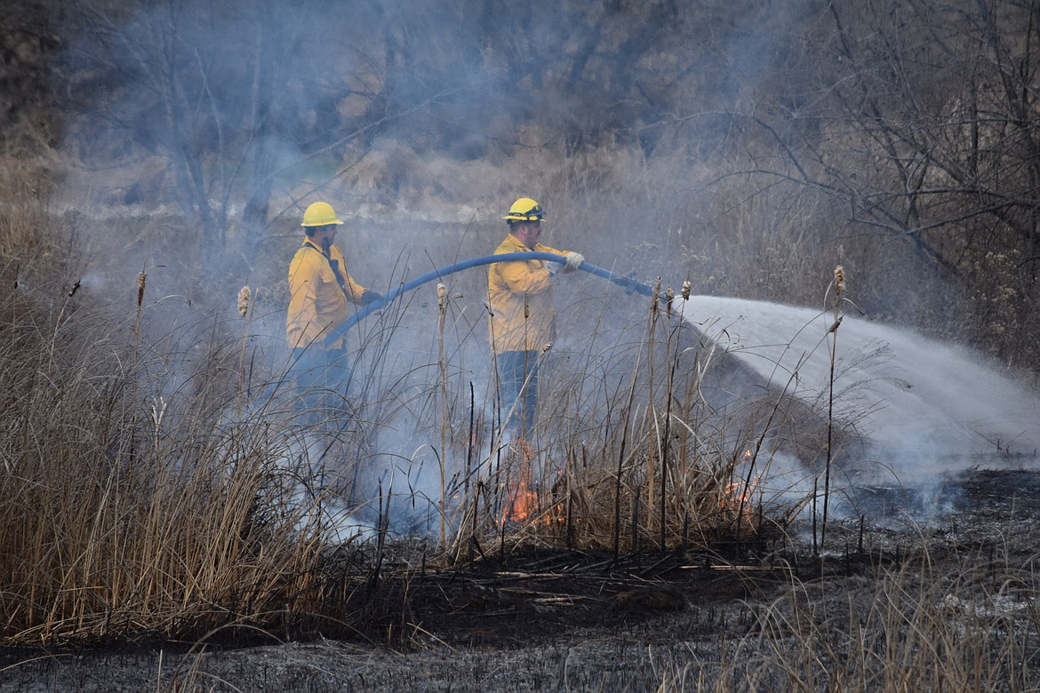 Charles H. Featherstone/Columbia Basin Herald
Moses Lake firefighters battle a small blaze on the island where  SR-17 crosses Crab Creek.