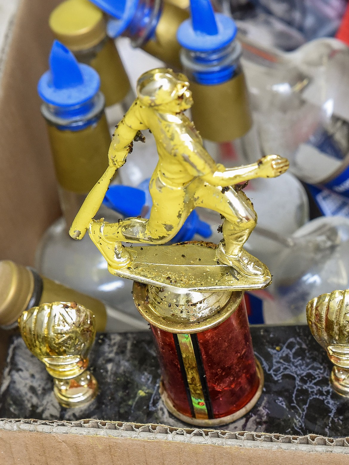 A trophy that did not escape the destruction sits in a box with empty bottles and other items during cleanup at Lee Gehring Memorial Field Monday. (Ben Kibbey/The Western News)
