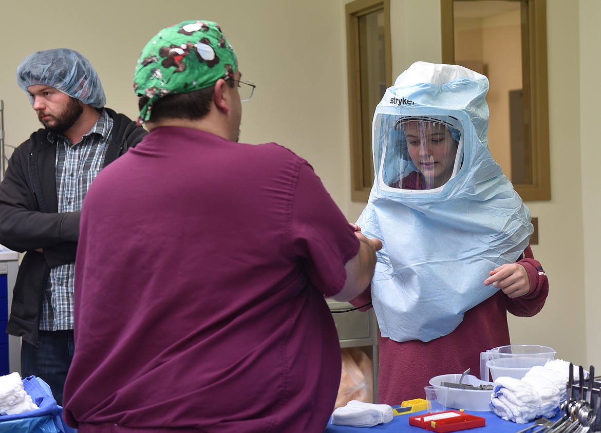 CLARK FORK Valley Hospital Surgery Technician Warren Hill helps Hallie Corbin with a surgeon&#146;s hood during the March 21 open house at the Plains facility.