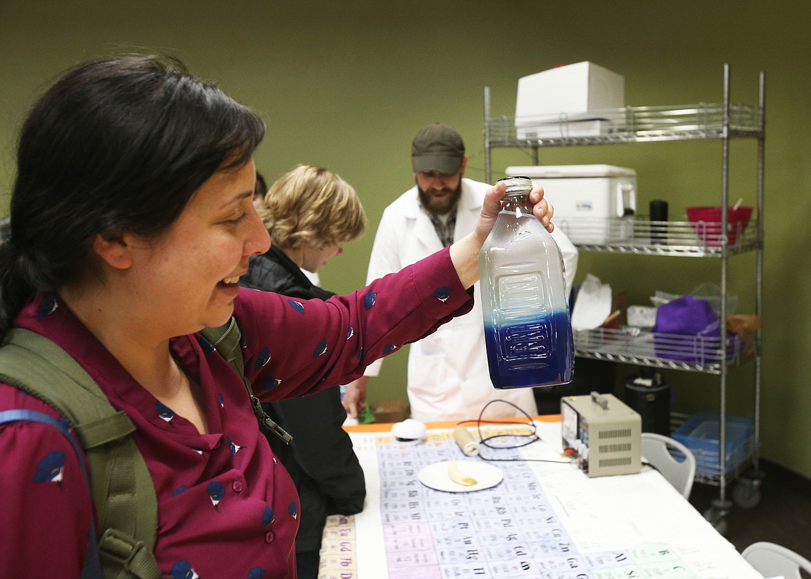 Krystal Saunoa, an environmental science student, watches as liquids of different densities separate in a jar Thursday at North Idaho College's STEM Expo. (LOREN BENOIT/Press)