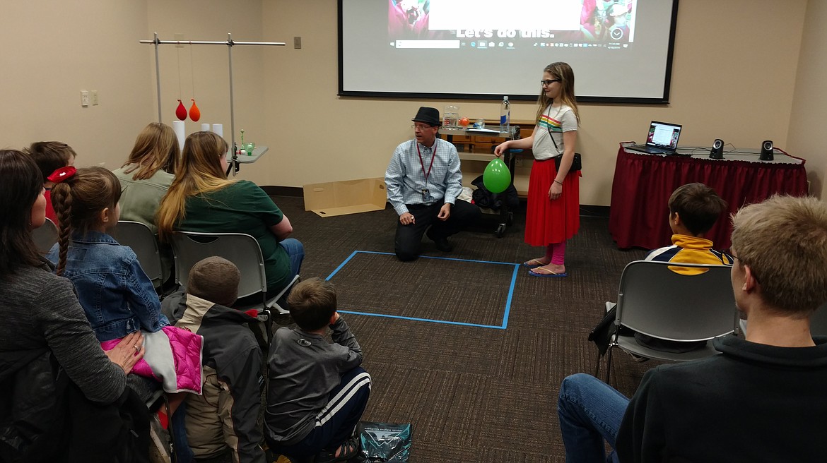 Chloe Cederquist, 10, of Coeur d'Alene, volunteers to hold a balloon for physics instructor David &quot;Doc&quot; Thompson during a very scientific air pressure experiment Thursday at the North Idaho College STEM Expo. (DEVIN WEEKS/Press)