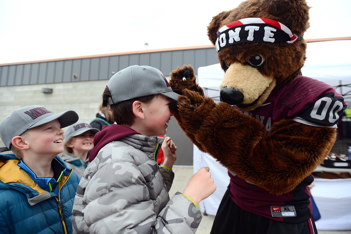 Monte, the Montana Grizzlies mascot, signs the hat of Owen Dodrill, 10, of Whitefish, before the Spring Game at Legends Stadium in Kalispell on Saturday. (Casey Kreider/Daily Inter Lake)