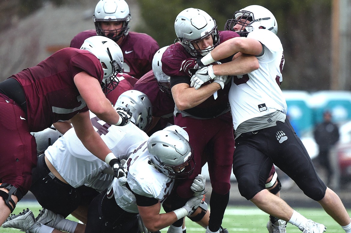 Montana Grizzlies linebackers Michael Matthews (52), left, and Patrick O'Connell (58), right, from Glacier High School, wrap up running back Adam Eastwood (25) in the Spring Game at Legends Stadium in Kalispell on Saturday. (Casey Kreider/Daily Inter Lake)