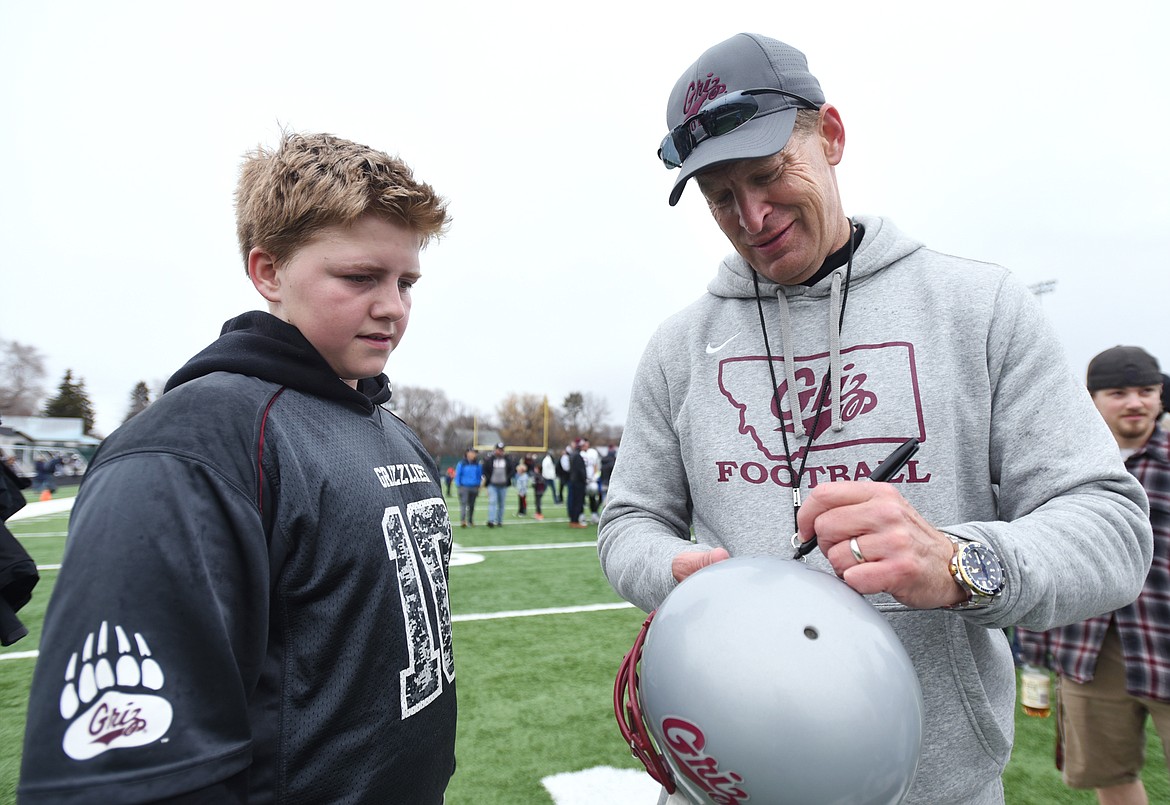 Montana Grizzlies head coach Bobby Hauck signs a helmet for Cody Vergeront, 12, of Evergreen, after the Spring Game at Legends Stadium in Kalispell on Saturday. (Casey Kreider/Daily Inter Lake)