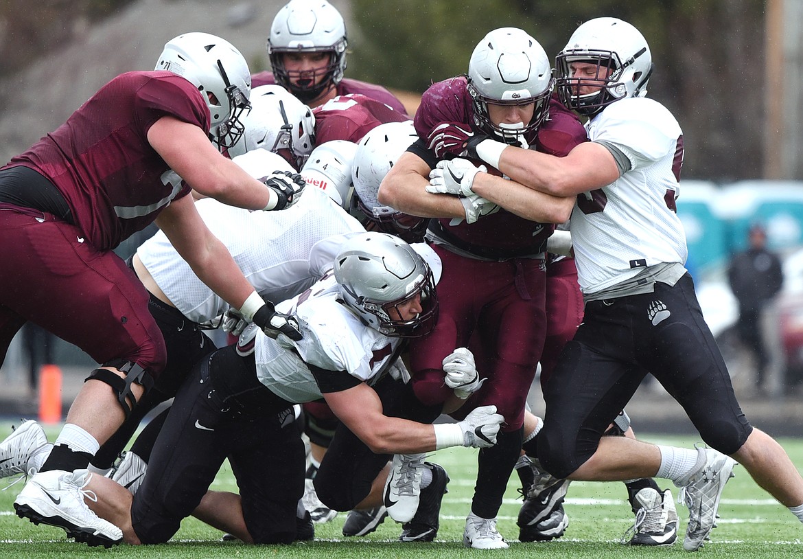 Montana Grizzlies linebackers Michael Matthews (52), left, and Patrick O'Connell (58), right, from Glacier High School, wrap up running back Adam Eastwood (25) in the Spring Game at Legends Stadium in Kalispell on Saturday. (Casey Kreider/Daily Inter Lake)