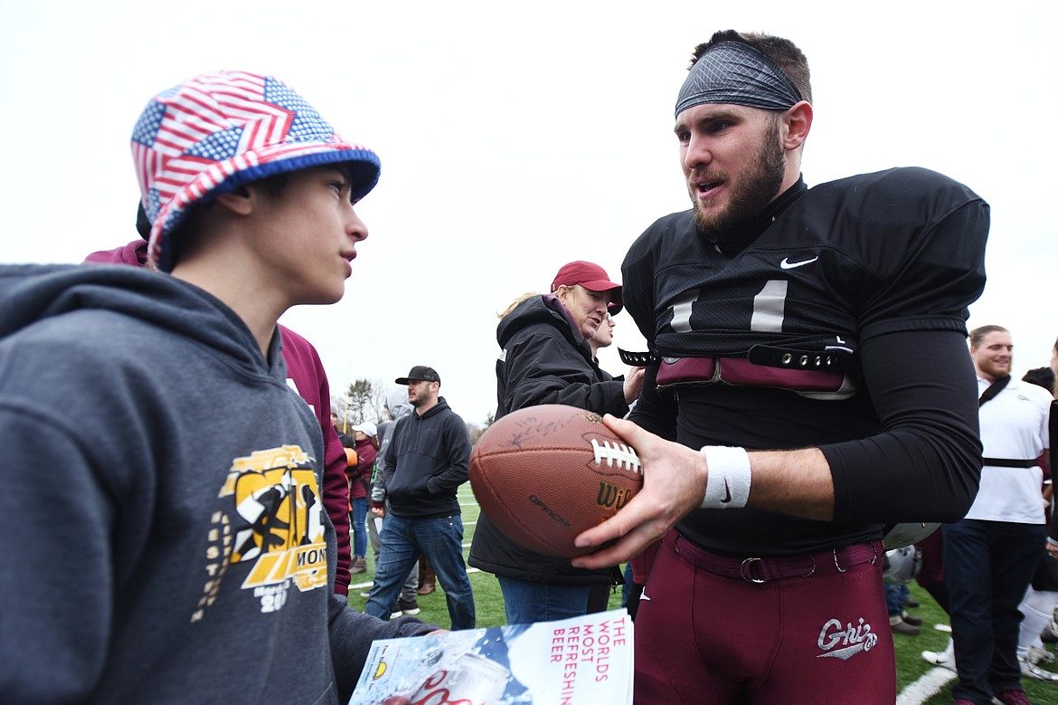 Montana Grizzlies starting quarterback Dalton Sneed (11) signs a football  for Tyler Gilfry, of Columbia Falls, after the Spring Game at Legends Stadium in Kalispell on Saturday. (Casey Kreider/Daily Inter Lake)