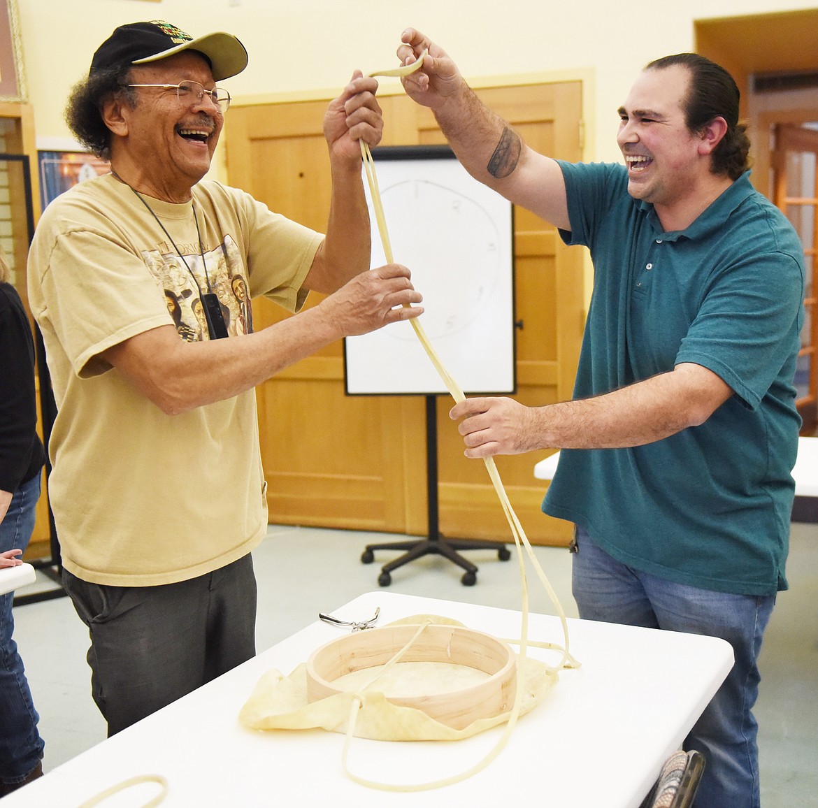 PEOPLE&#146;S CENTER Education Instructor Jordan Stasso, right, has a laugh with Tom Camel while they stretch rawhide laces used to attach a tanned hide to a cedar hoop. The activity took place March 27 at the People&#146;s Center in Pablo.