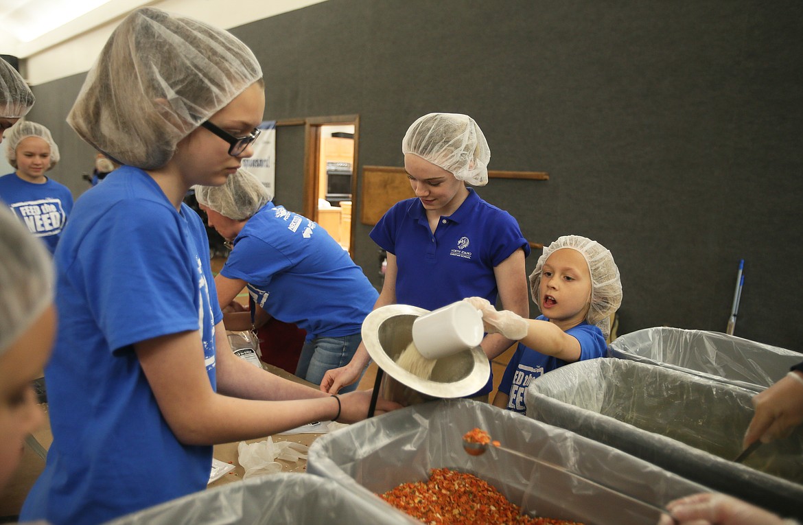 DEVIN WEEKS/Press
North Idaho Christian School third-grader Miri Claridge pours a serving of soy protein into a bag held by seventh-grader Emma Vonlind during a Feed the Need packing party in North Idaho Christian School&#146;s gym on Thursday. NICS students raised more than $53,000 to support their school and pack more than 10,000 meals to send to kids in Haiti. Also pictured: seventh-grader Maggie Thomas.