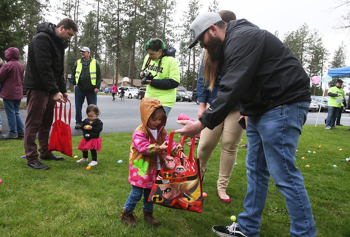 Annelyn Rodriguez, 2, of Coeur d&#146;Alene, inspects an egg before she drops it into the bag held by her dad, Aaron Rodriguez, Saturday morning during the Easter egg hunt at the Church of the Nazarene in Coeur d&#146;Alene. (DEVIN WEEKS/Press)
