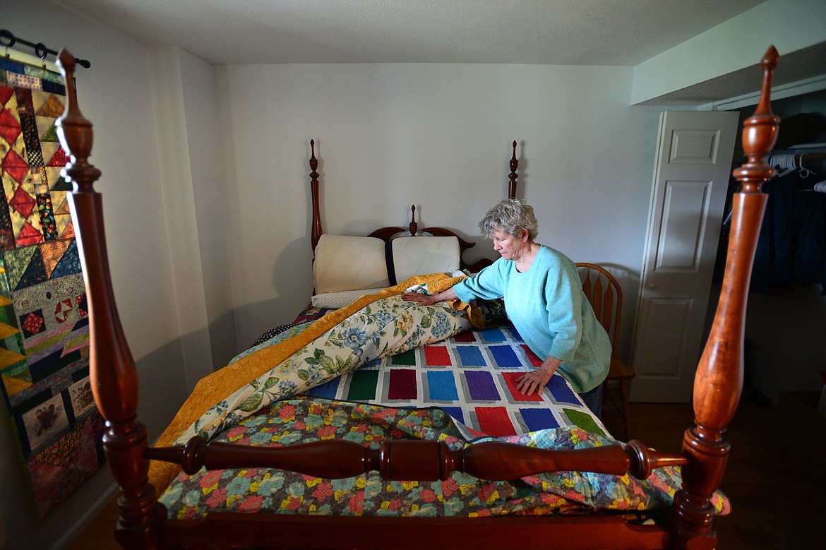 Ellen Metzger shows a bed in a spare bedroom of her home covered in her colorful quilt creations.