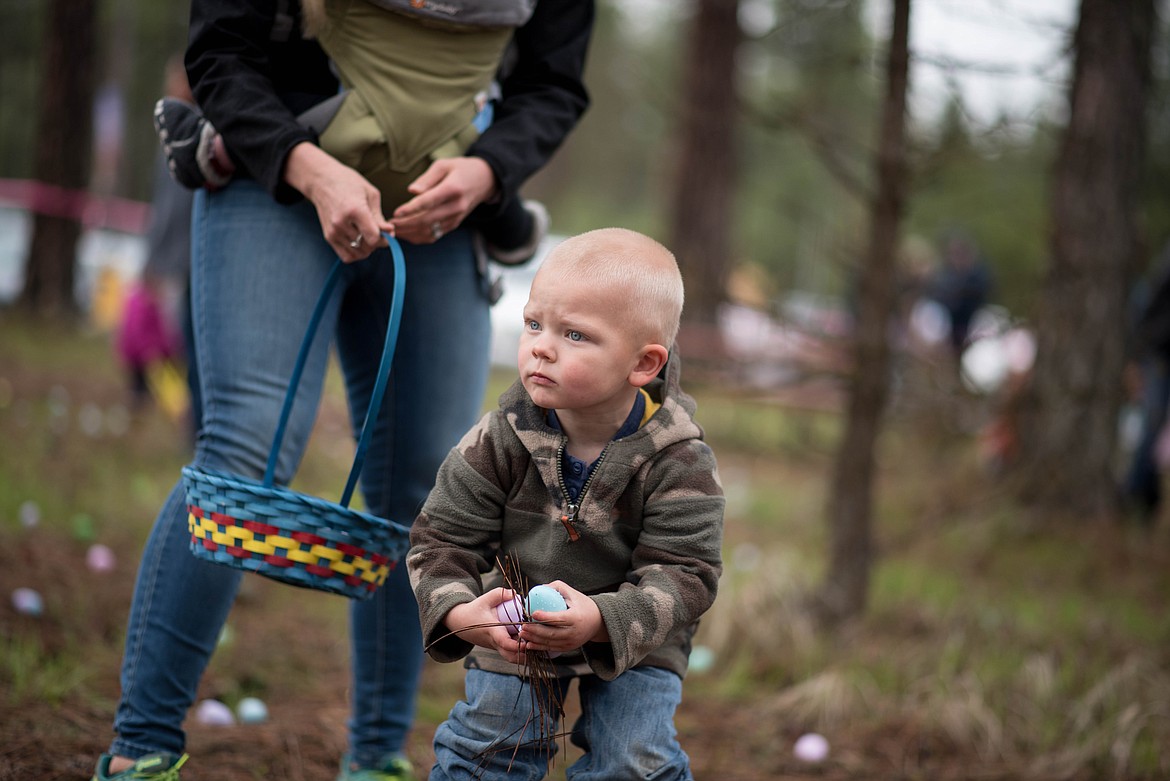 Clyde Farrand, 3, picks up a little more than just eggs during the Easter Eggstravaganza Egg Hunt, Saturday at the Libby Christian Church. (Luke Hollister/The Western News)