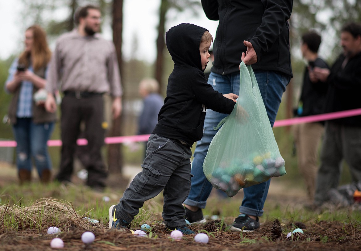 Kyle Clemons, 2, loads up his bag during the Easter Eggstravaganza Egg Hunt, Saturday at the Libby Christian Church. (Luke Hollister/The Western News)