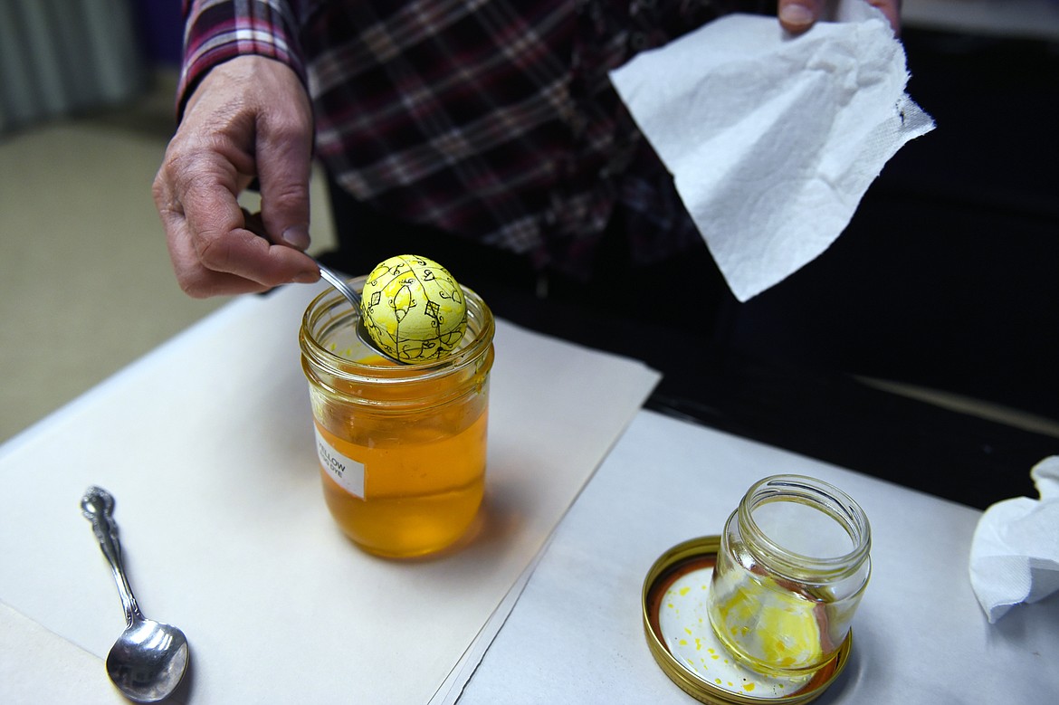 Kathy Martin scoops an egg out of a container of yellow egg dye while making Ukrainian Easter eggs at the museum.