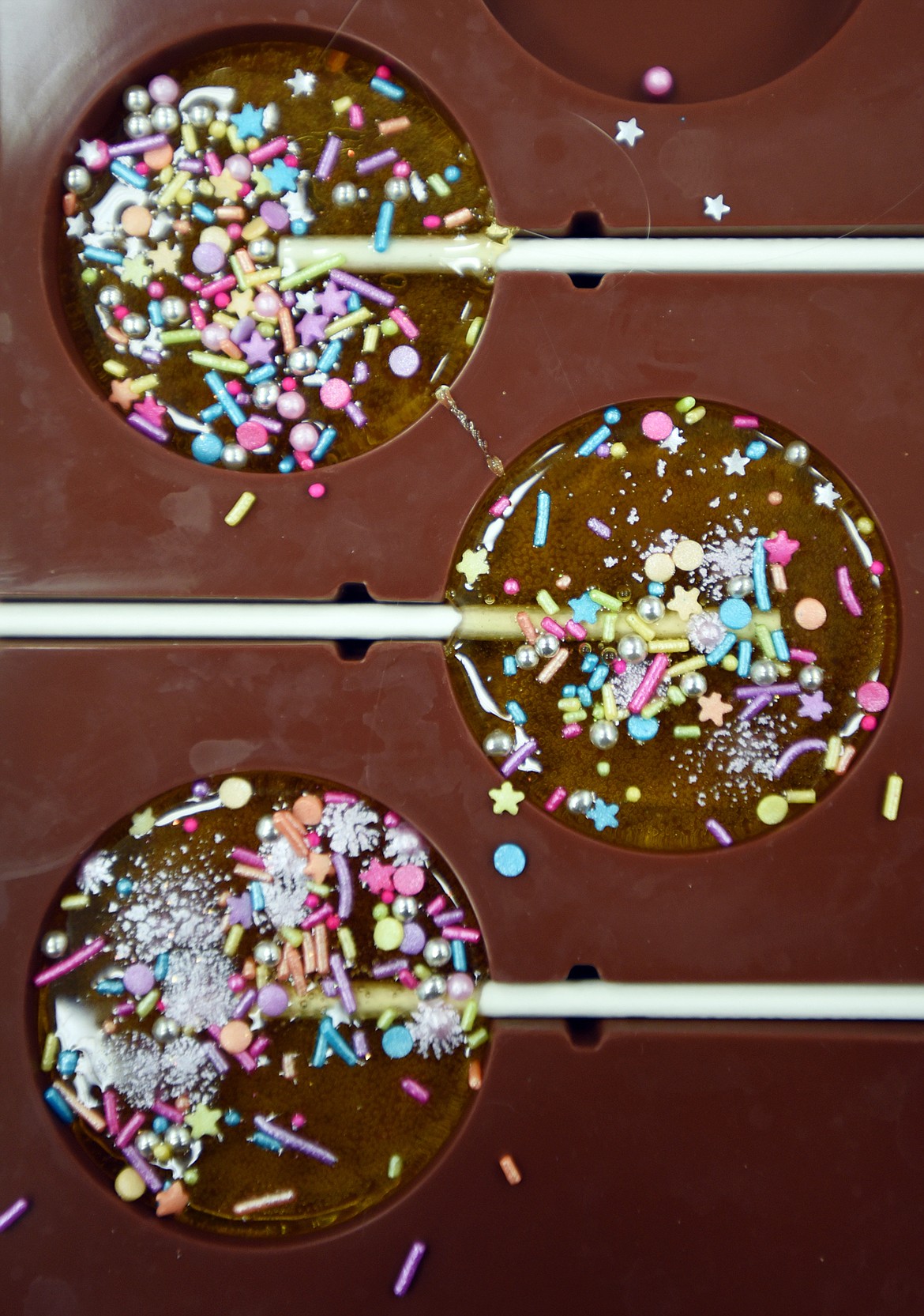 Detail of three Birthday Cake lollipops still in their mold decorated with sprinkles. Stephanie Murray, owner of Fiddlestix Candy Co. can add multiple details to the lollipops to make them personalized to her client.