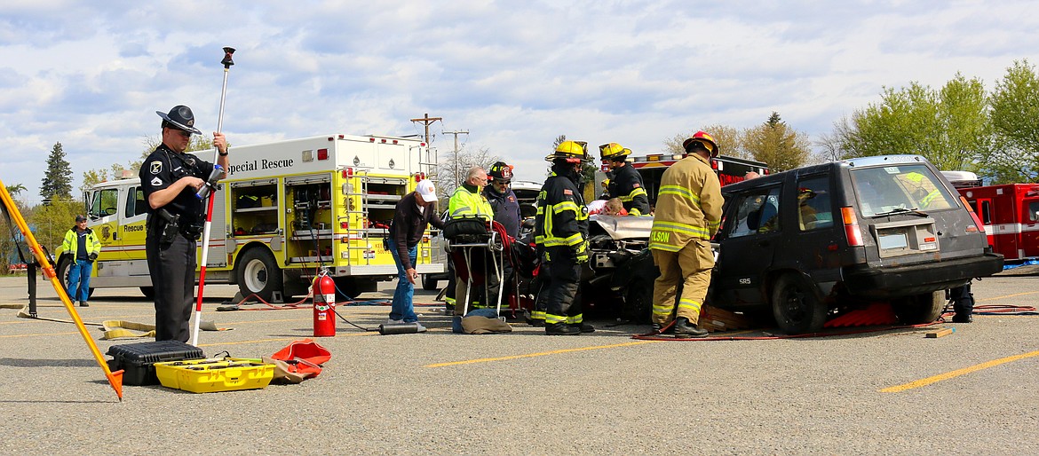 Photo by MANDI BATEMAN
Idaho State Police Trooper Dustin Kralik working the scene of the mock crash, while firefighters work on extricating the students from the two cars.