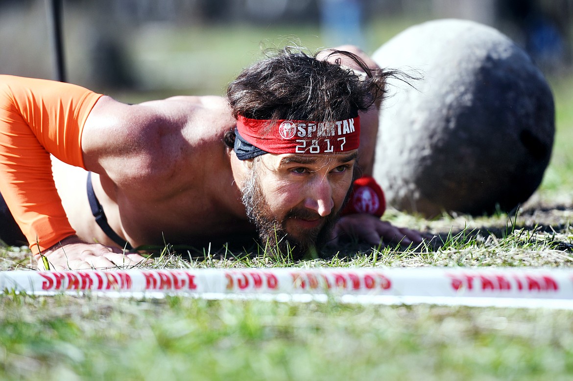 A competitor performs burpees as part of the Atlas Carry obstacle during the 13-mile Spartan Beast race at Flathead Lake Lodge in Bigfork on Saturday. (Casey Kreider/Daily Inter Lake)