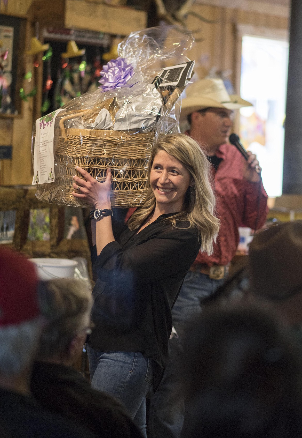 Helen Carpenter holds a basket of goodies while onlookers bid for it at a Wings fundraiser, Saturday at the Yaak River Tavern and Mercantile. (Luke Hollister/The Western News)