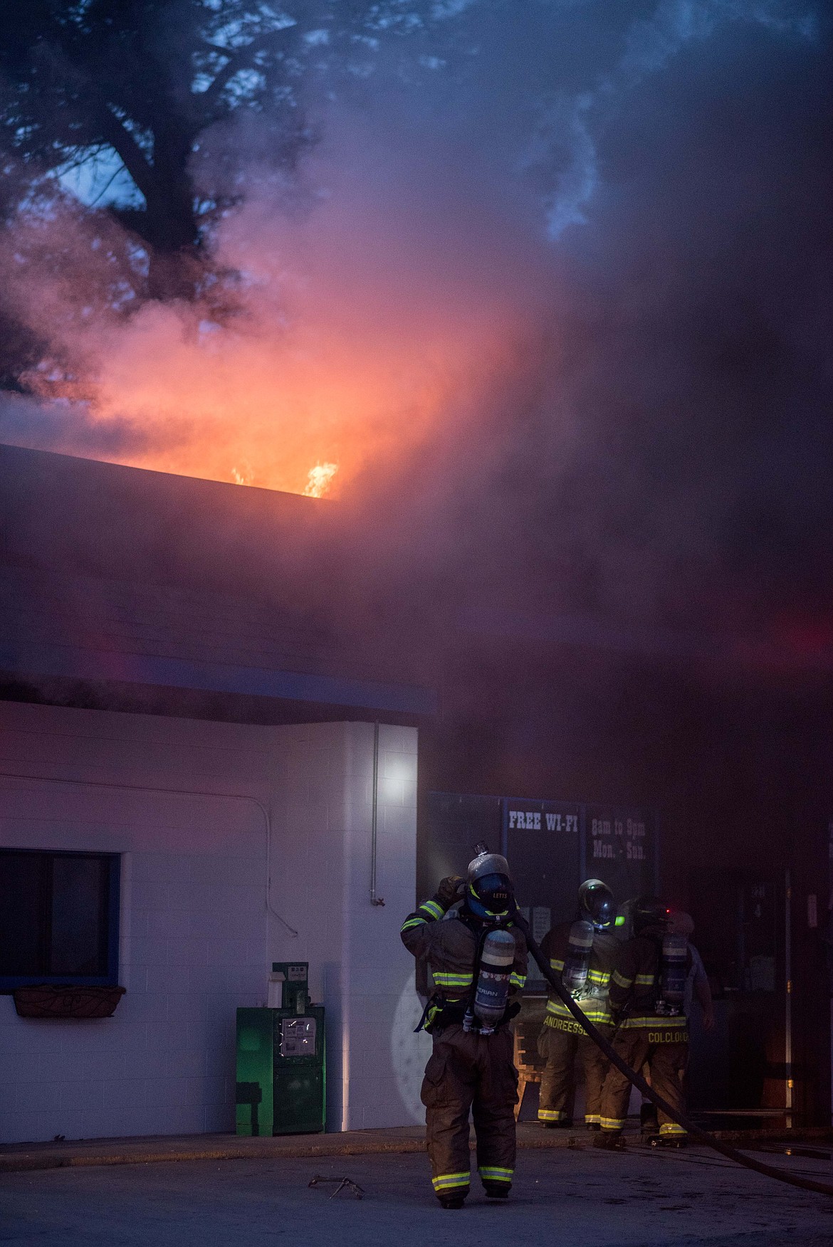 Firefighters rush to put out a fire at Moody&#146;s Dirty Laundry &amp; Self-Service Dog Wash, Friday night in Libby. (Luke Hollister/The Western News)