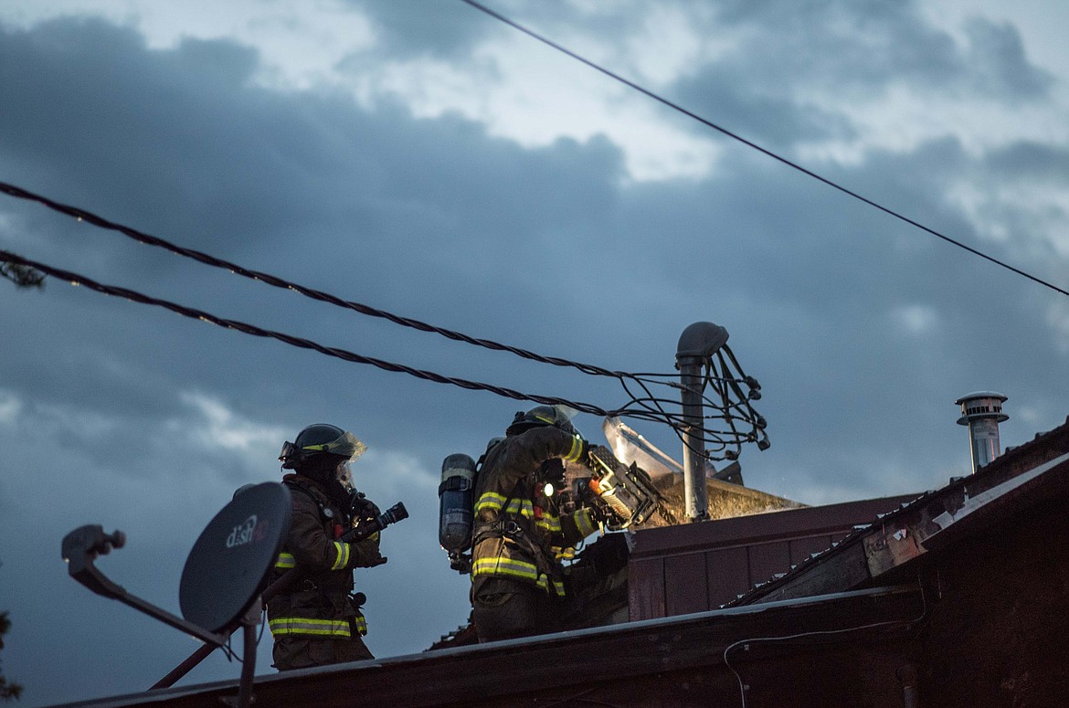 Fire crews chainsaw off parts of the roof while attempting to access a fire inside of Moody&#146;s Dirty Laundry &amp; Self-Service Dog Wash, Friday night in Libby. (Luke Hollister/The Western News)