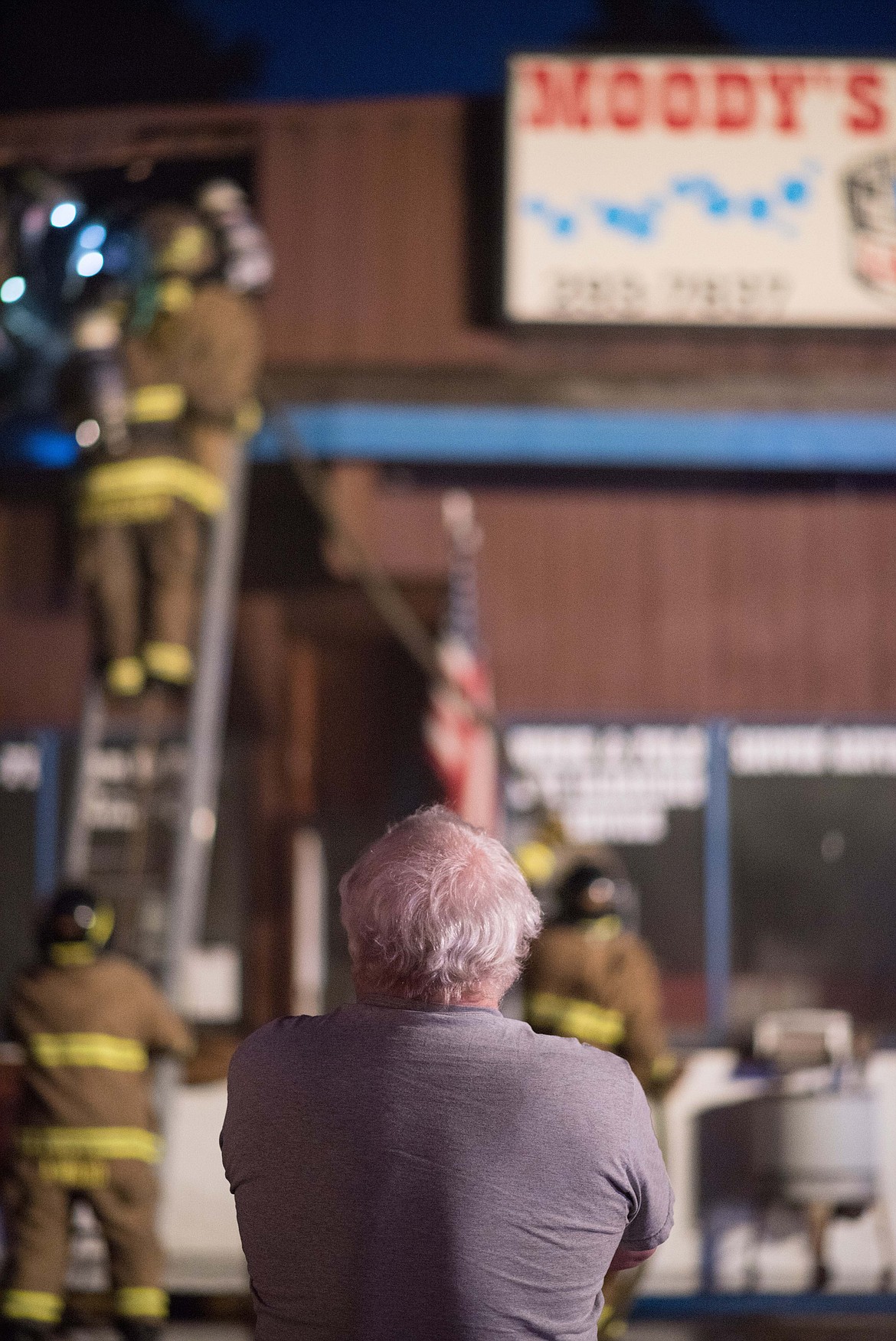 Jay Moody, Owner of Moody&#146;s Dirty Laundry &amp; Self-Service Dog Wash, watches as fire crews tear off parts of his roof while attempting to access the fire, Friday night in Libby. (Luke Hollister/The Western News)