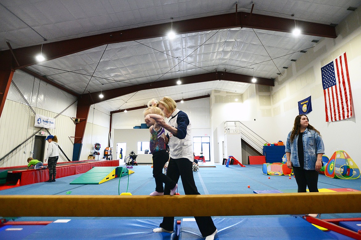 Glacier Gymnastics director Annie Rose helps a young gymnast across the balance beam during a Parent/Tot program on Thursday, May 2. (Casey Kreider/Daily Inter Lake)