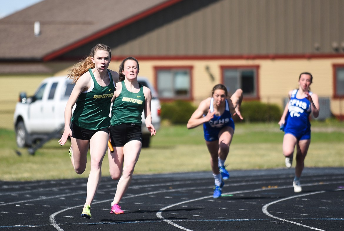 Emily Gunlikson hands the baton off to Lauren Schulz in the 400 meter relay at Columbia Falls last Tuesday. (Daniel McKay/Whitefish Pilot)