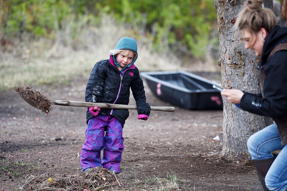Portia McCaffree of Columbia Falls pauses during the Hunt Montana cleanup effort to snap a photo of her daughter Wynn, 3.