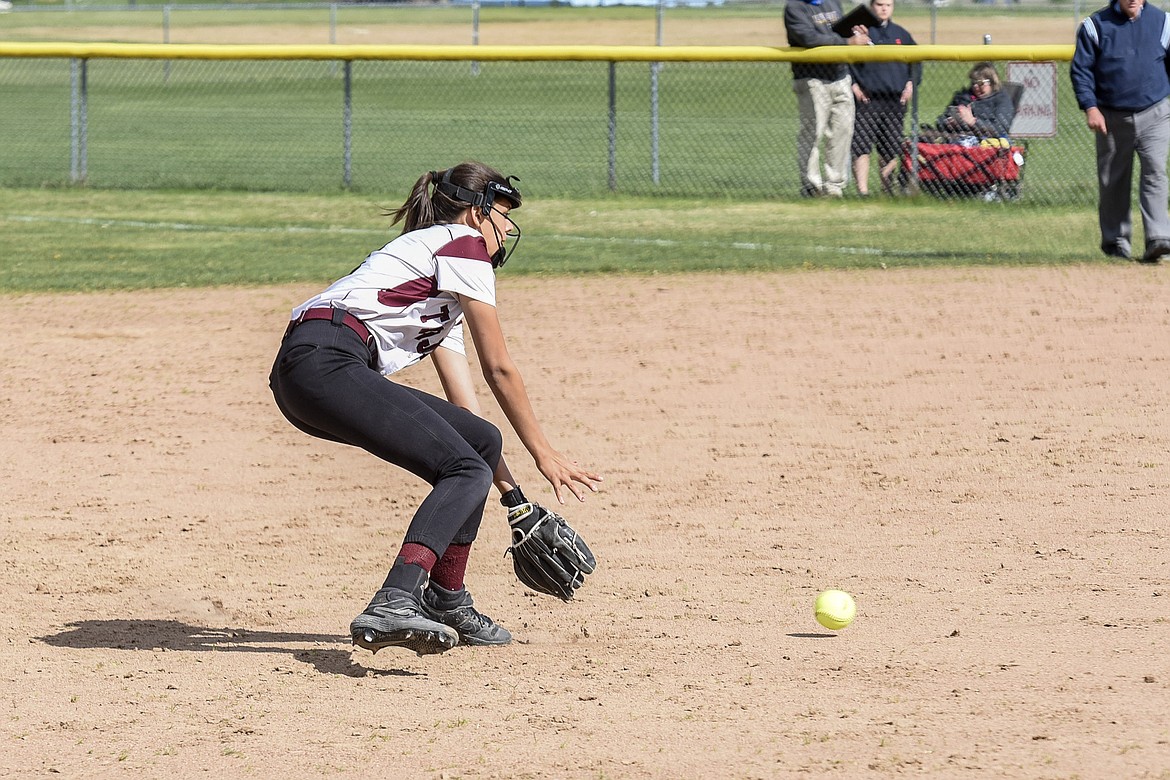 Troy sophomore shortstop Talise Becquart stoops to scoop up a ground ball before tossing it to senior Tristyn Winebark at first for the first out, top of the third inning, during the Troy-Libby varsity game at Troy, April 30. (Ben Kibbey/The Western News)