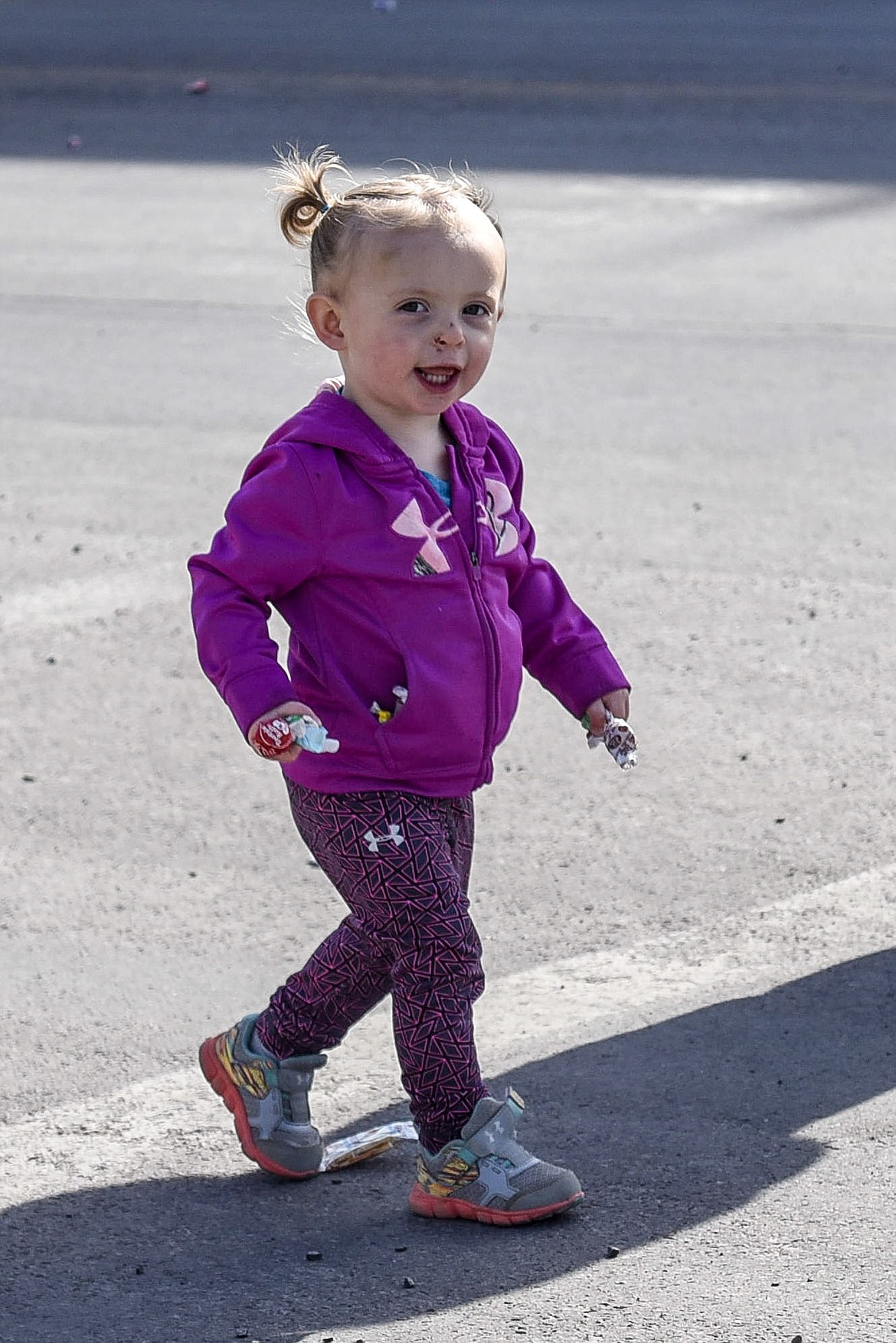Gracie Scofield heads back up Mineral Avenue with pockets and hands full of candy after the Opening Day Parade in Libby, Saturday. (Ben Kibbey/The Western News)