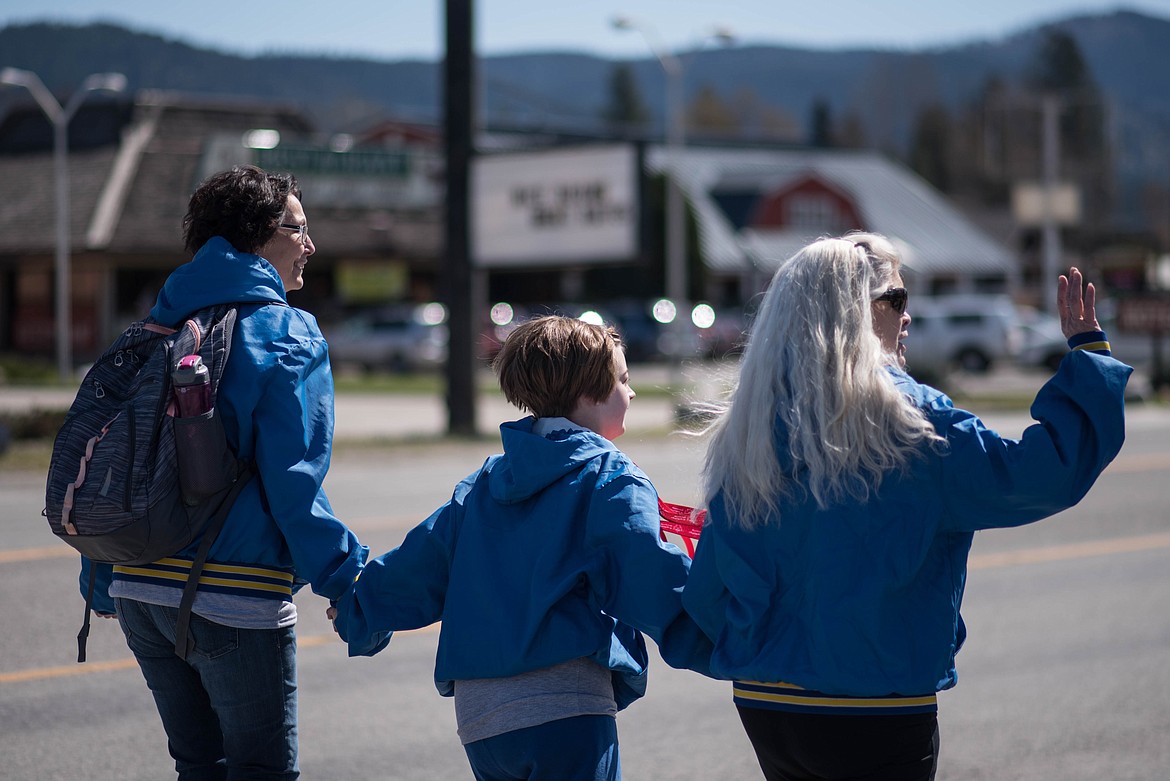 Participants wave at family members while walking through town during the Law Enforcement Torch Run for Special Olympics, Monday in Libby. (Luke Hollister/The Western News)