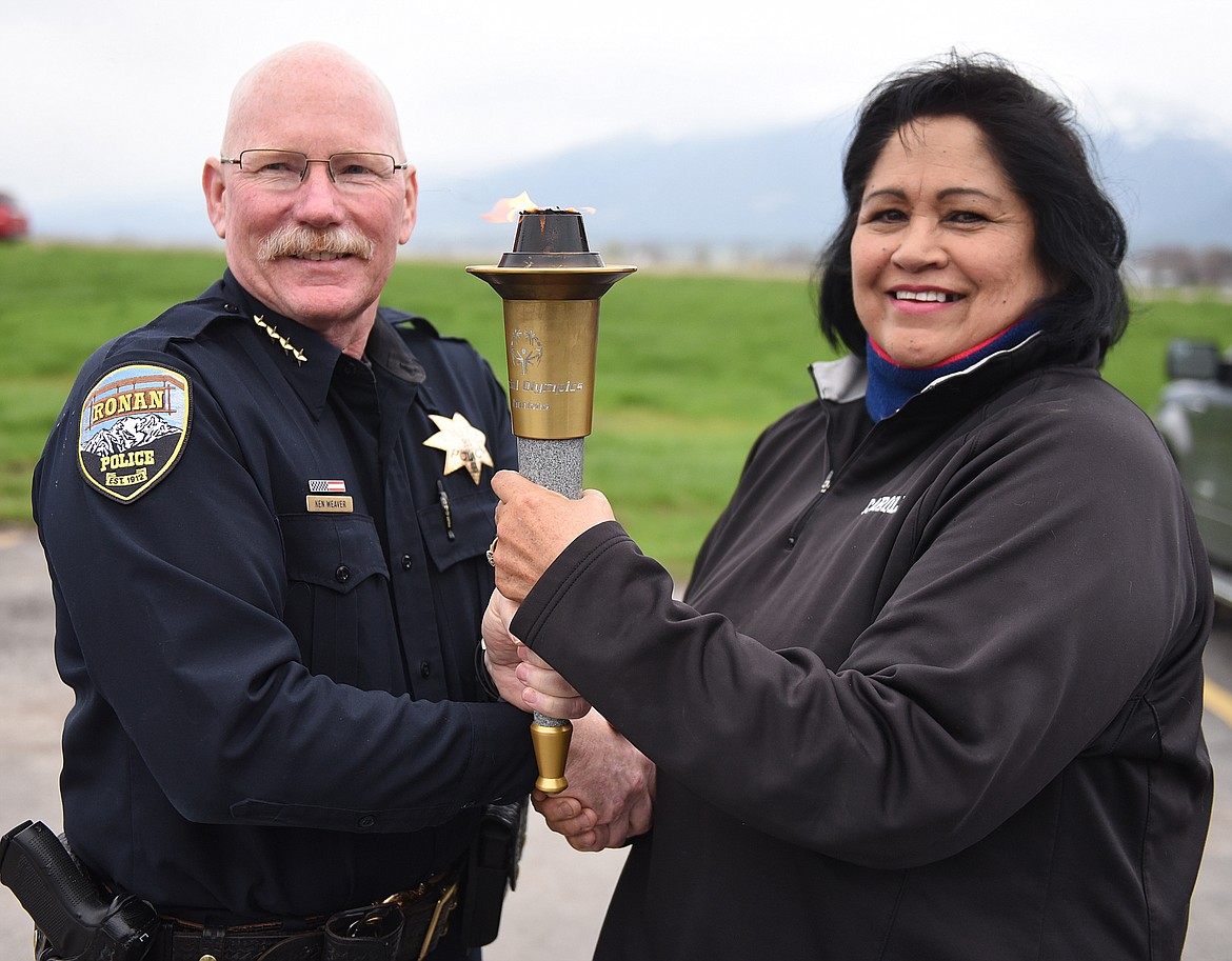 CONFEDERATED SALISH and Kootenai Tribal Council member Carole Lankford passes the torch to Ronan Police Chief Ken Weaver.