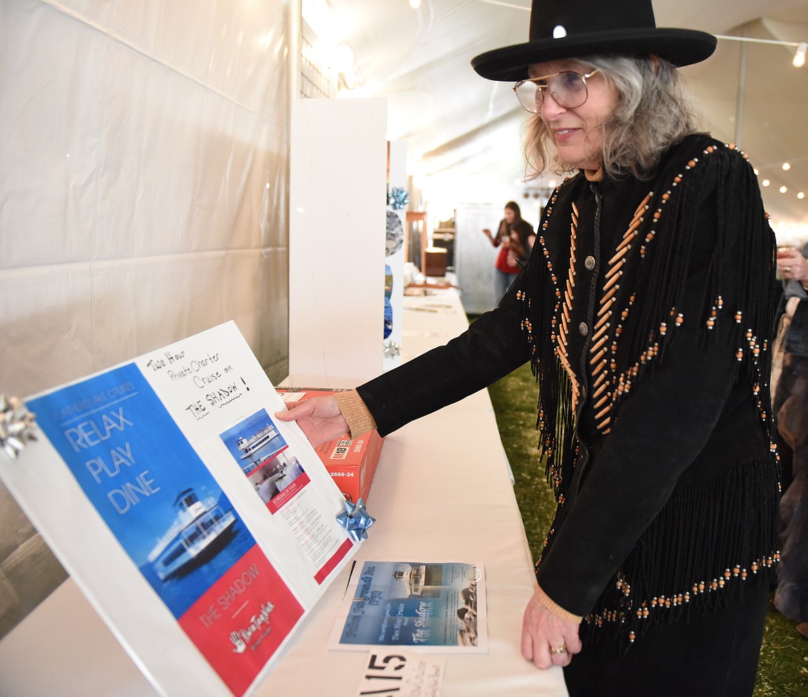 BARBRA STONE takes a close look at the description of the cruise on Flathead Lake on The Shadow that was a live auction item during the Cowboy Ball at the Polson Fairgrounds on Saturday night, April 27. (Joe Sova photos/Lake County Leader)