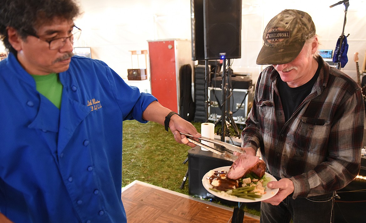 GUY HILL, co-owner of Little Montana in Ronan, serves a generous slice of succulent prime rib to Cory Wolfe during the Cowboy Ball at the Polson Fairgrounds.