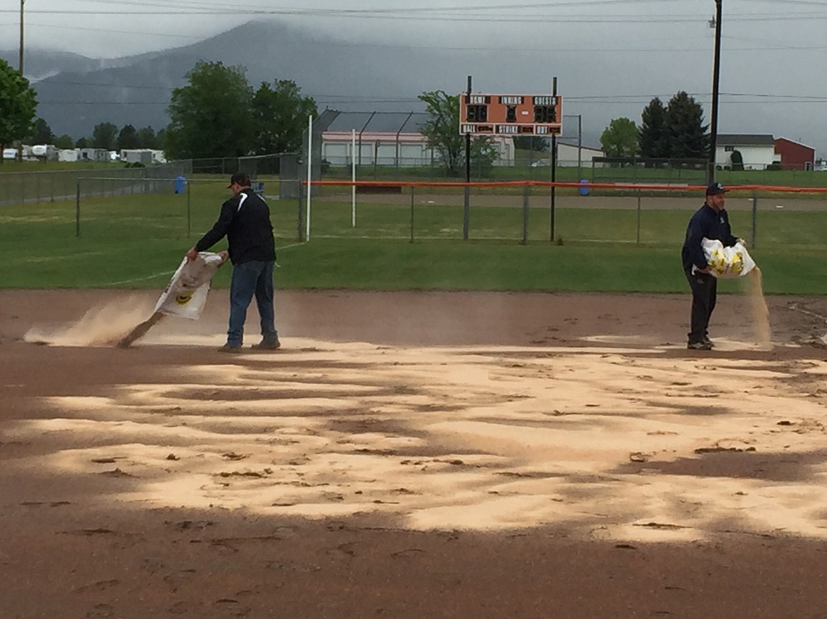 MARK NELKE/Press
Volunteer grounds crew members, coaches and players helped empty bags of Diamond-Dry on the two softball fields at Post Falls High on Friday morning. Two games and part of a third in the state 5A tournament were played, before a steady rain forced play to be postponed until today.