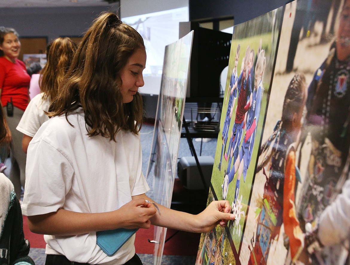 Celeste Lowe, 12, places a sticker on the soccer fields poster at the unveiling of the new Youth Center plans Tuesday in Worley. (LOREN BENOIT/Press)