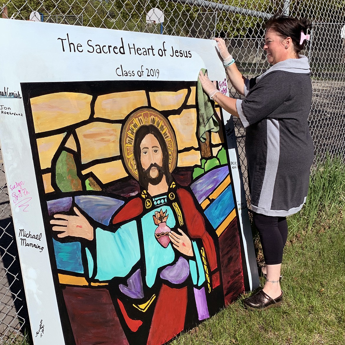 Art teacher Jennifer Griffith wipes away soot from a painting created by eighth-graders at St. Matthew&#146;s School depicting one of the church&#146;s stained glass windows. The painting had been stored in the basement. (Hilary Matheson/Daily Inter Lake)