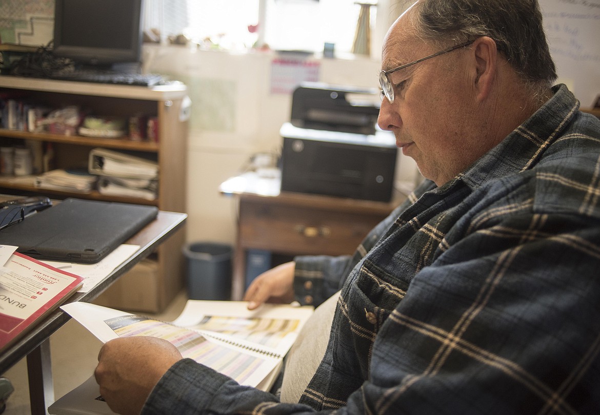 Dan Williams, Lincoln County Weed Department head, flips through pages of different noxious weeds, April 30 at the Weed Department shop in Libby. (Luke Hollister/The Western News)