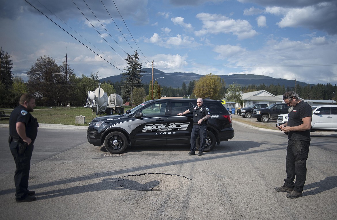 Libby police officers block off part of Montana Avenue due to a sinkhole in an intersection, Tuesday in Libby. On scene, Mayor Brent Teske, right, said the sinkhole is probably due to a water main leak.