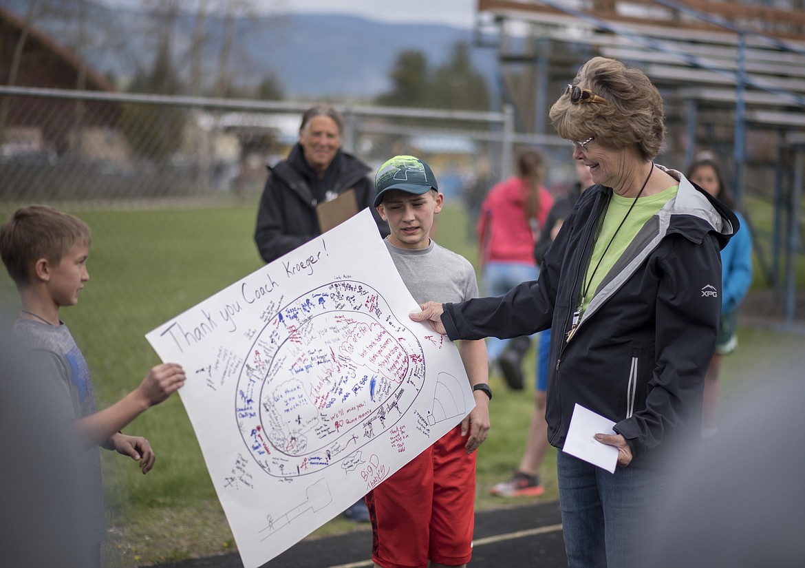 Students hand Coach Marge Kroeger a thank you poster with signatures and notes written all over it at the end of the 4th and 5th grade Mini Meet, Thursday, May 2, at Libby High School. Kroeger said she has put a lot of students through the Libby track program. One of the notes reads &#147;you are the best track teacher.&#148; (Luke Hollister/The Western News)