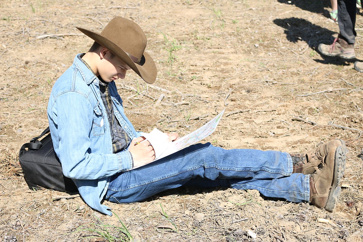 (Photo by MARY MALONE)
A Clark Fork Jr/Sr High student gets comfortable while testing his map reading skills at the Idaho State Forestry Contest on Thursday at the Delay Farm in Careywood.