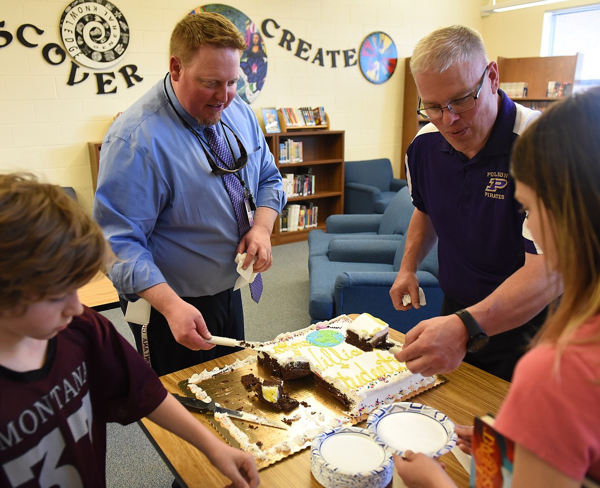 POLSON MIDDLE School celebrated a gathering to accept the SMART Schools Recycling Challenge Champion banner and a check for $1,000 to be used for the recycling program with a cake Monday afternoon. Cutting and serving the cake are PMS Assistant Principal Jesse Yarbrough, left, and teacher Luke Mills.